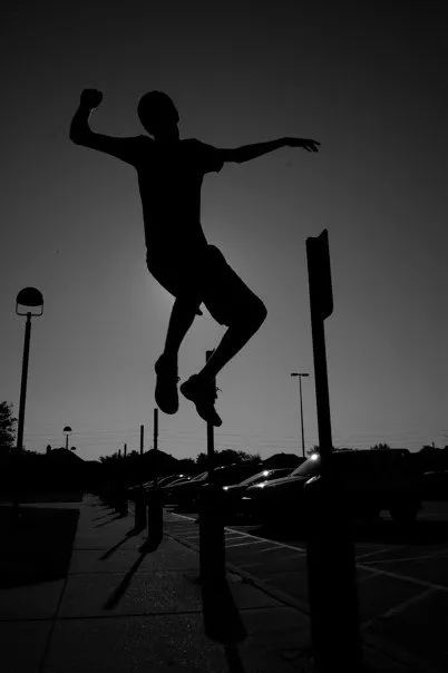 A silhouette of a man jumping in the air.