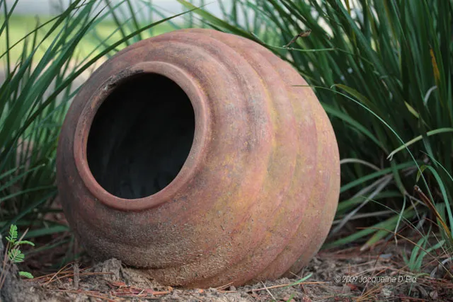 A clay pot sitting on the ground.
