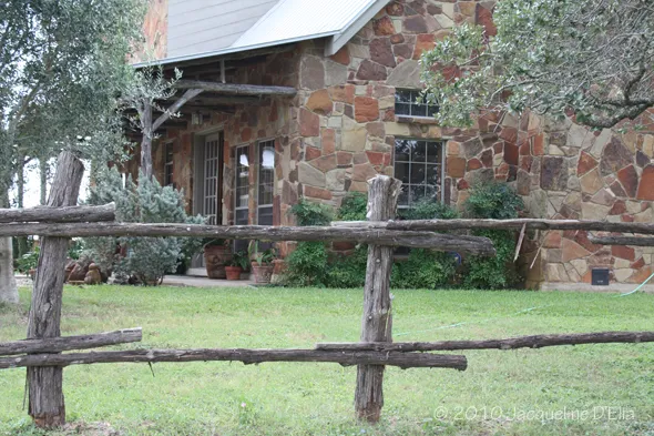 A wooden fence in front of a stone house.