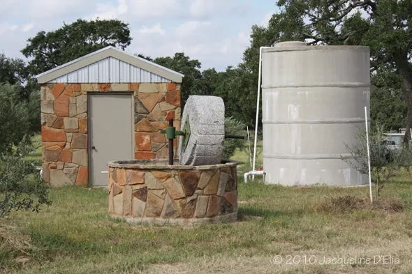 A stone building with a water tank in the middle of a field.
