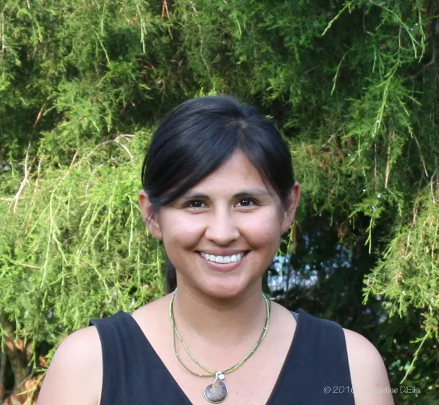 A woman smiling in front of a tree.