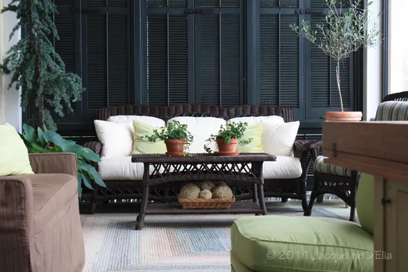 A living room with wicker furniture and green plants.