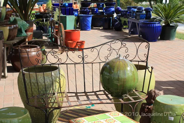 A bench in front of a display of potted plants.