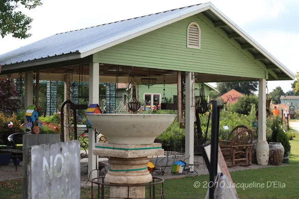 A green shed with a birdbath in the yard.