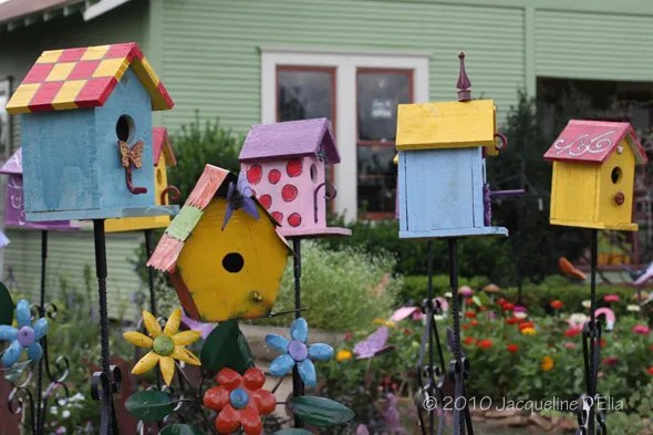 Colorful birdhouses in front of a house.