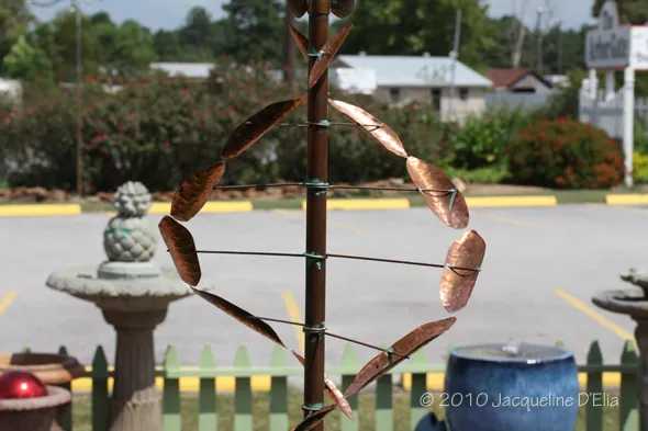 A metal wind chime in a parking lot.