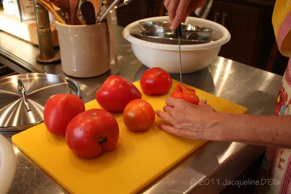 A woman is canning tomatoes on a yellow cutting board.