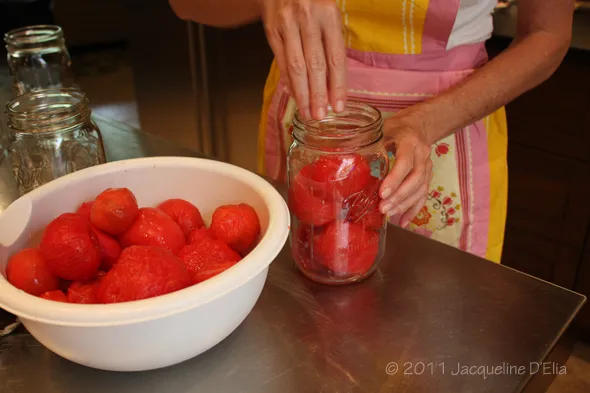 A woman is canning tomatoes.