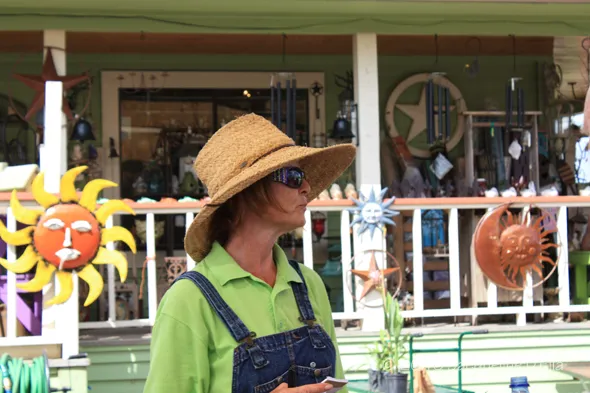 A woman wearing overalls and a hat.