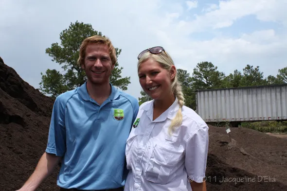 A man and woman standing in front of a pile of dirt.