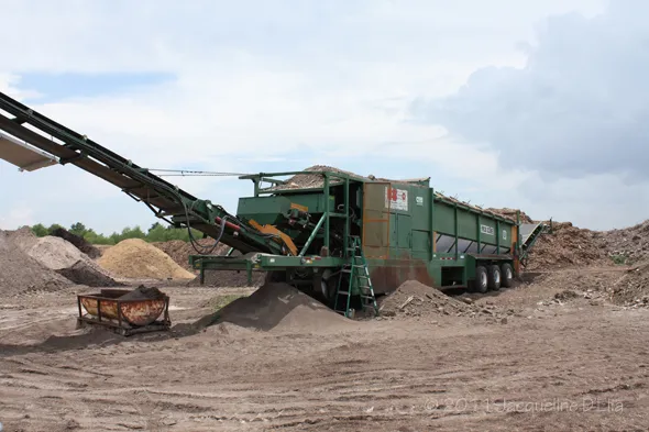 A green machine in a dirt field.
