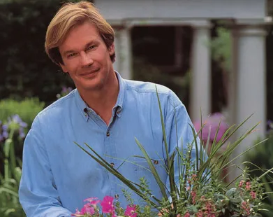 A man in a blue shirt holding a flower pot.