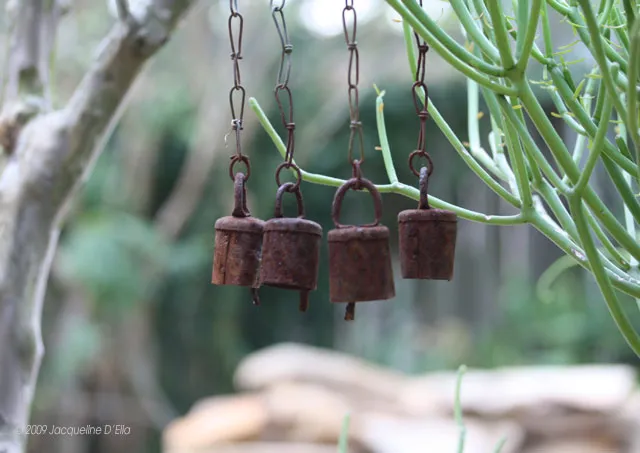 A group of rusty bells hanging from a tree.