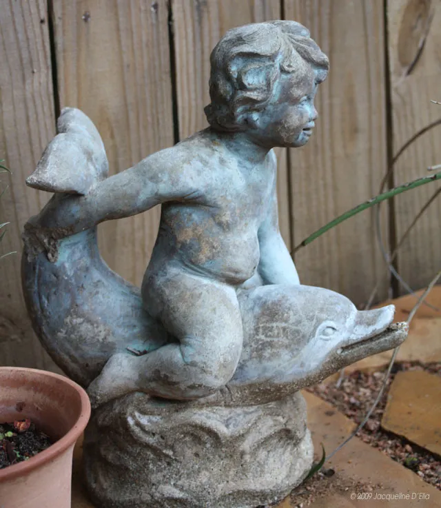 A statue of a baby sitting on a dolphin.