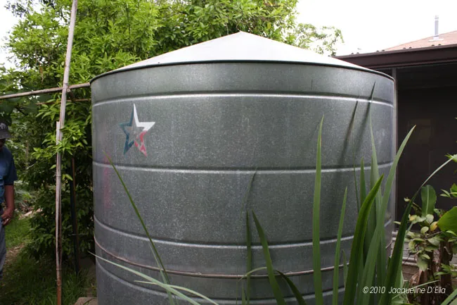A man standing next to a large metal water tank.
