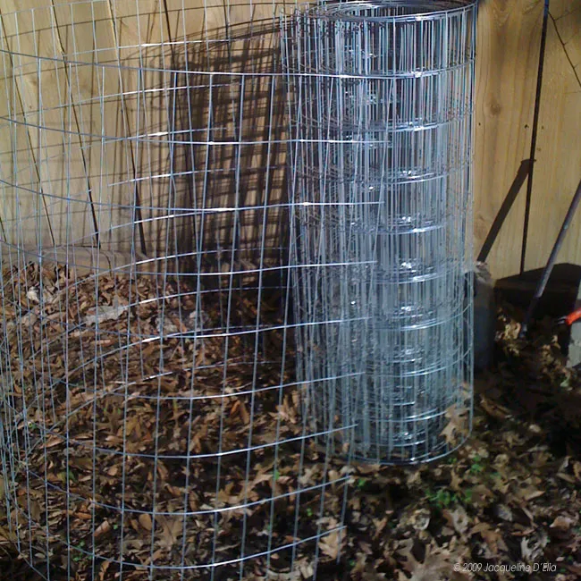 A wire fence covered in leaves serves as a compost bin.
