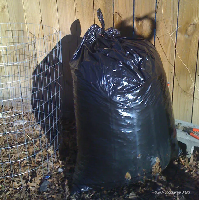 A compost bin next to a wooden fence.