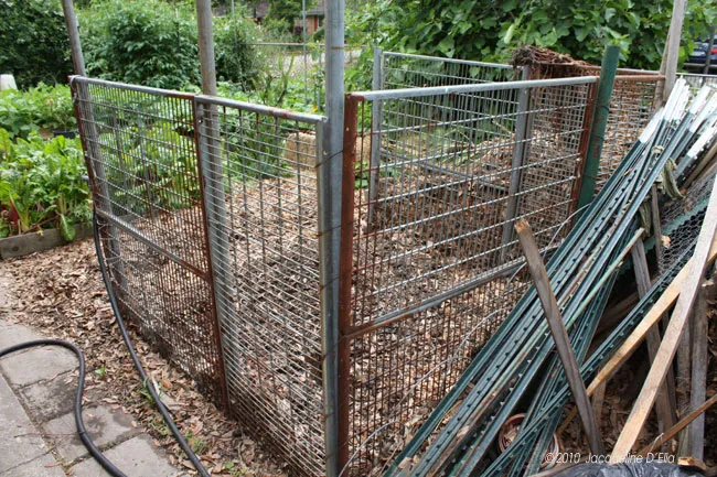 A garden with a metal fence and a hose.