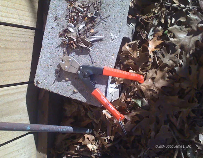 A pair of pliers near a compost bin.