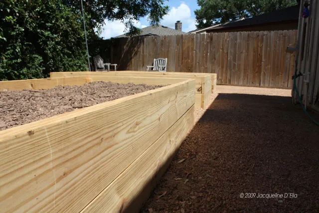 A wooden raised garden bed in a backyard.