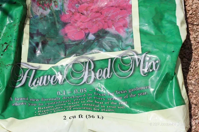 A bag of flower bed mix on the ground.