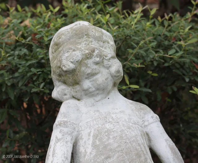 A statue of a little girl in a garden.