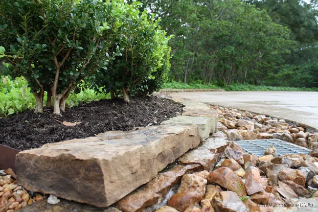 A rock retaining wall in front of a house with a kitchen garden.