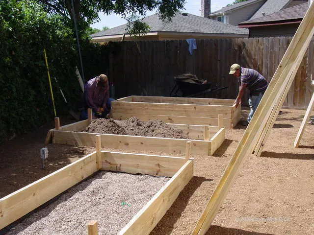 Two men working on a raised garden bed.