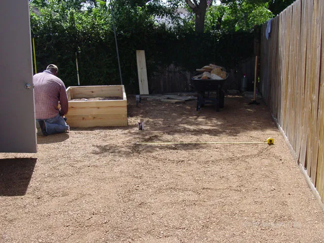 A man is working on a garden in a backyard.
