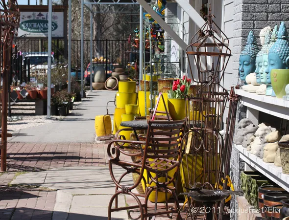A row of pots and vases on a sidewalk in front of a store.