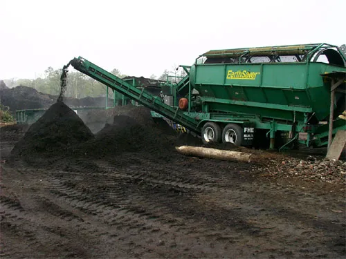A green truck with a pile of dirt.