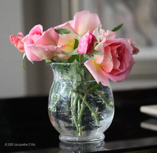 Pink roses in a glass vase on a table.