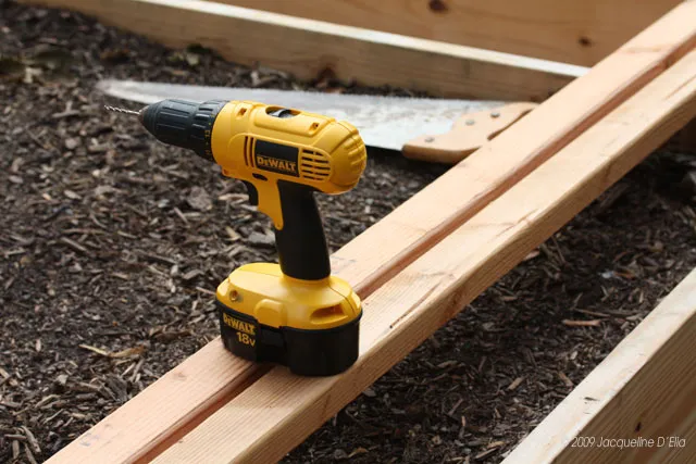 A dewalt drill sits on top of a wooden vertical trellis.
