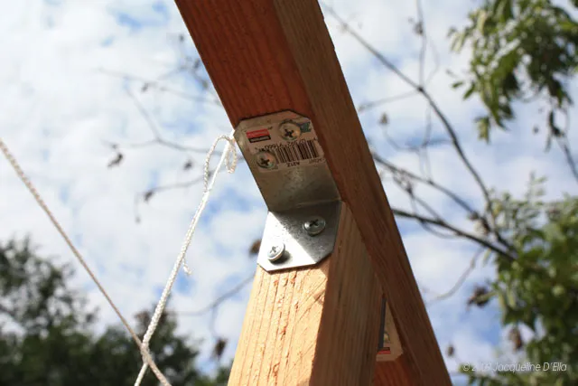 A close up of a wooden beam with a vertical rope attached.