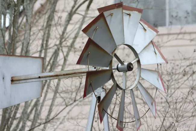 A windmill in front of a house.